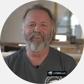 Pete Ribaudo, an experienced action master craftsman, smiles in a workshop with over 40 years of dedication to piano restoration