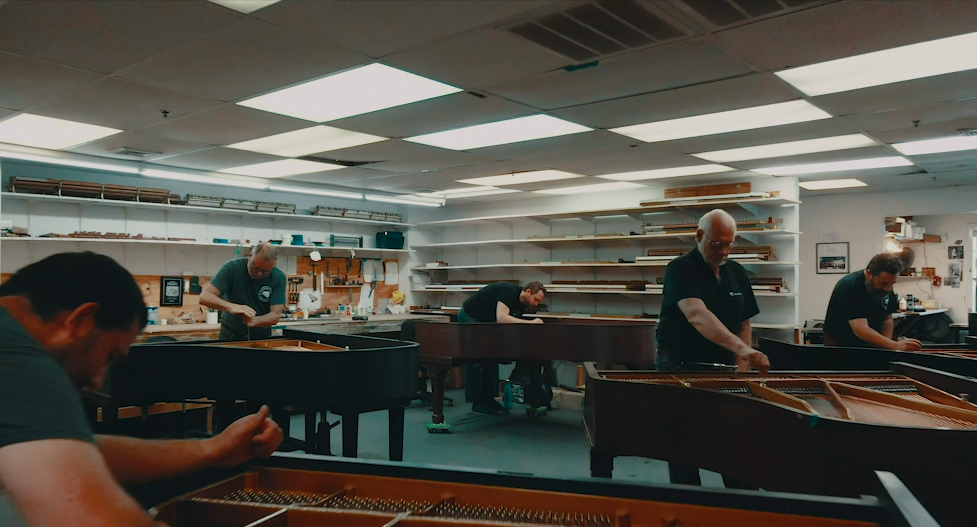 Five craftsmen restoring grand pianos in the workshop