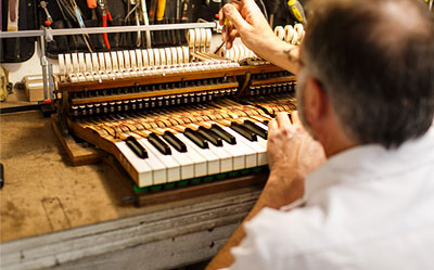 A master technician examining the components of a piano's action.