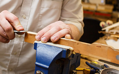 Technician repairing a single piano key held in a vice.